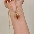 Detailopname van een gouden vuurwerk hanger ketting met zirkonia op een vrouwenpols - Goud