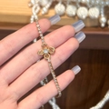 Dettaglio macro del bracciale a fiori dorati con zirconi scintillanti su una mano - Oro