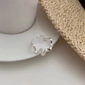 Detailed close-up of a silver irregular wave ring resting on a white ceramic dish - Silver