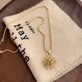 Detalle de collar de estrella dorada con circonitas sobre fondo de tela rústica - Collar de Fuegos Artificiales Dorado