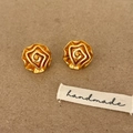 Detailed view of handmade golden spiral camellia stud earrings on a kraft background - Camellia Stud Earrings / Gold