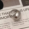 Detailweergave van een dikke zilveren waterdruppelring op vintage krantenachtergrond - Vloeibare Waterdruppel Ring (C-217)