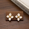 Détail de boucles d'oreilles fleurs en émail blanc et finition dorée sur socle en bois - Clous d'Oreilles Fleur à Quatre Pétales Émail Blanc (A-1262)
