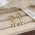 Close-up of golden hoop earrings featuring white five-petal flower charms on beige background - White Enamel Small Flower Earrings (A-487)