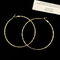 Dettaglio di grandi orecchini a cerchio dorati con finitura martellata e chiusura a perno - Cerchio 6cm / Oro