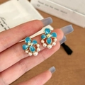 Close-up of blue flower stud earrings with gold petals and white pearls detail - Blue Enamel Stud Earrings