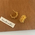 Detailed view of golden irregular starburst C-shape earrings with a handmade label - Gold