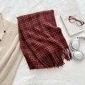 Deep red plaid scarf with tassel edges styled on soft white textured fabric - Red
