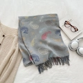 Grey knit paisley scarf with colorful patterns and fringe details on a flat lay surface - Gray