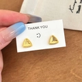 Macro view of gold triangle stud earrings with textured finish and micro-bead edges - Gold Earrings / Gold
