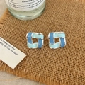 Detail of square geometric woven earrings with blue enamel finish on burlap surface - Blue Enamel Stud Earrings