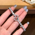 Pulsera de corazón plateada con gema verde y circonitas blancas sobre fondo de madera - Estilo de Corazón de Calabaza de Circonita Verde / Verde