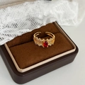 Primer plano de anillo vintage dorado con gema roja ovalada y circonitas brillantes - Dorado con circonita roja