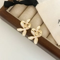 Détail de boucles d'oreilles fleuries avec cadre doré et émail blanc nacré dans un écrin - Blanc/Crème