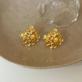 Detalle macro de pendientes de racimo de flores doradas en plato de cerámica y luz - Dorado
