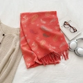 Orange red paisley knit scarf with twisted tassels displayed on white bed linen - Orange Red
