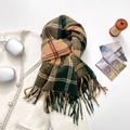 Forest green and camel plaid scarf with long tassels laid over white knitwear - Green & Brown