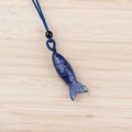 Hand-carved blue stone fish pendant with deep blue woven cord on bamboo wood background - Blue Spot Stone