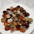 Close-up of apple-shaped natural striped agate pendants with polished silver metal bails - Red Agate