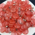 Dettaglio di pendenti circolari in quarzo rosa con ganci in metallo argentato in un vassoio - Rosso Anguria (Sintetico)