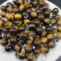 Spherical tiger eye stone bead pendant with silver metal bail on a white plate - Tiger's Eye
