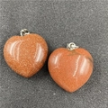 Detailed close-up of heart-shaped gold sandstone pendants with shiny metallic clasps - Synthetic Goldstone