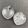 Macro shot of two transparent heart crystal pendants with silver metal clasps on a black mat - White Crystal
