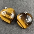 Macro shot of two polished heart-shaped tiger eye stone pendants with silver clasps - Tiger's Eye