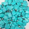 Rectangle turquoise stone pendants with black veins and silver bails in a bulk display - Synthetic Blue Turquoise