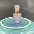 Detail of faceted amethyst perfume bottle pendant with gold metal cap on a display base - Amethyst