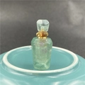 Macro shot of green fluorite crystal perfume bottle with gold cap and natural texture - Fluorite