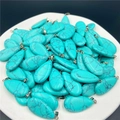 Dettaglio di ciondoli a goccia in turchese con ganci argentati su piatto bianco - Turchese Blu