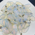Stack of teardrop opalite crystal pendants with silver metal bails on a white tray - Opal