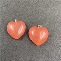 Detail van twee oranje agaat hart hangers met zilveren oogjes op een donkere ondergrond - Watermeloen Rood
