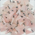 Close-up of bulk pink crystal triangle stone pendants with polished silver metal bails - Rose Quartz