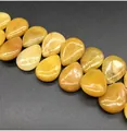 Macro shot of polished teardrop yellow jade beads with natural textures on black surface - 13x18mm Yellow Jade