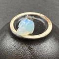 Vue macro d'un pendentif tête de mort en opale avec bélière en argent sur céramique - Opale Synthétique