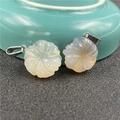 Macro shot of carved agate flower pendants with silver metal clasps on a ceramic bowl - Grey Agate