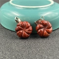 Close-up of red agate flower pendants with intricate carvings and silver metal clasps - Rainbow Stone