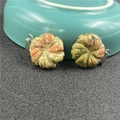 Macro shot of two carved unakite flower pendants with silver bails on a textured background - Unakite