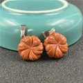 Close-up of gold sandstone flower pendants with metallic bails on ceramic dish - Synthetic Goldstone