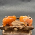 Gros plan de deux pendentifs en forme d'éléphant sculptés dans de la cornaline orange - Agate rouge