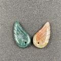 Detailed view of carved stone angel wing pendants in green and orange with drill holes - India Agate