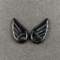Close-up of polished black wing-shaped pendants with abstract curved engravings for DIY jewelry - Obsidian