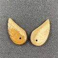 Macro detail of hand-carved natural stone angel wing pendants with fine feather textures - Jasper