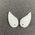 Close-up of white carved angel wing pendants with detailed feather texture and single hole - White Jade