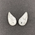 Detailed macro view of white turquoise angel wing pendants with natural marble texture - Howlite