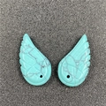 Detailed macro view of two blue turquoise angel wing pendants with natural stone textures - Synthetic Blue Turquoise