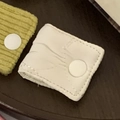 Faux leather and corduroy cable organizers with white snap buttons on wood surface - Quilted White