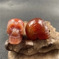 Handcrafted red agate skull pendants with detailed carvings and a smooth polished finish - Red Agate
